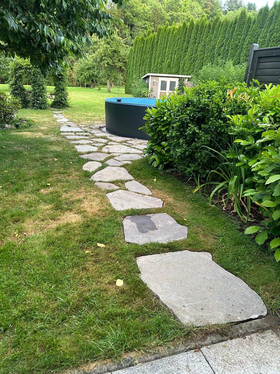 Natursteinweg durch gepflegten Rasen
